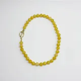 Collar de cuentas esféricas de jade amarillo de 10 mm, con nudos separadores en hilo naranja y cierre tipo toggle en acero con baño de oro.