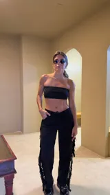 Pantalón negro de gamuza con flecos en los laterales, tiro alto y ajuste con cordones.