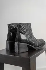 Conjunto de dos piezas compuesto por una musculosa de cuello redondo y un pantalón de corte recto, ambos en color negro. El pantalón incluye un cinturón ancho con hebilla metálica circular.