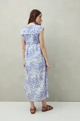 Vestido largo con estampado geométrico en tonos azul, marrón y beige. Tiene escote en V con lazos ajustables, mangas cortas y corte holgado.