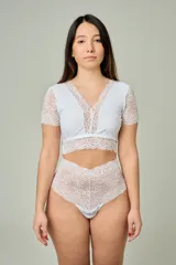 Conjunto de lencería blanco compuesto por un corpiño corto con mangas cortas y detalles de encaje floral en el escote y bajo busto, y una bombacha hipster tiro alto completamente de encaje.