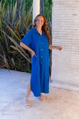 Vestido camisero de muselina color negro, de largo midi, con cuello clásico, manga corta y cierre frontal con botones.