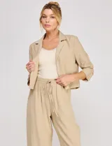 Blazer corto color beige de Allie Rose, confeccionado en mezcla de lino y viscosa, con frente abierto, solapas clásicas y mangas tres cuartos fruncidas.