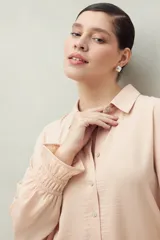 Camisa negra de manga larga con cuello clásico y botones frontales. El tejido presenta una textura arrugada o plisada, y los puños tienen un frunce elástico.