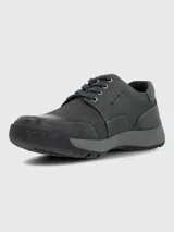 Zapato de cuero gris oscuro, estilo casual con cordones, punta redonda y suela de goma bicolor (gris claro y negro). Presenta costuras decorativas en el cuerpo del zapato y un pequeño logo grabado en el lateral.