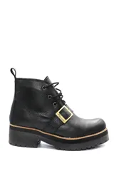 Borcego de cuero negro con cordones, suela track de plataforma y detalle de hebilla metálica dorada con logo grabado en el lateral.