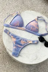 Conjunto de bikini con estampado tie-dye en tonos azul y naranja. El top es de estilo triangular con breteles regulables y cierre de gancho en la espalda. La bombacha es de corte vedetina con laterales fruncidos elásticos.