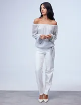 Blusa plateada de gasa lurex con escote off-shoulder, mangas largas abullonadas y terminación anudada en el ruedo.