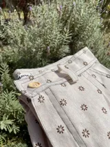 Pantalón de lino color crudo con estampado de flores marrones, corte recto y tiro alto.