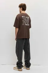 Remera marrón oversize de manga corta, con cuello redondo y pequeños estampados blancos en el pecho.