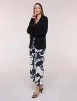 Blazer negro desestructurado de confección liviana y caída fluida, con cuello smoking, solapa corrida y mangas largas.