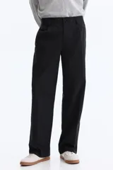 Pantalón sastrero color negro de corte relajado, confeccionado en mezcla de algodón y lyocell, con pliegues frontales y bolsillos laterales.