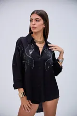 Camisa negra de manga larga con detalles de lentejuelas y bordados en el pecho, cuello camisero y cierre de botones.