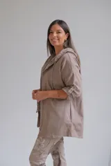 Campera tipo parka liviana color visón, con cierre frontal, capucha con cordones ajustables y mangas 3/4 con detalle de trabilla. Presenta un diseño holgado y casual.