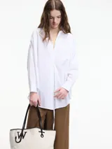 Camisa blanca de algodón con cuello camisero y cierre frontal con botones.