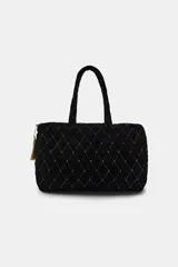 Bolso tipo shopper acolchado confeccionado en terciopelo negro. Presenta un diseño de rombos con hilo metalizado y aplicaciones de brillos en las intersecciones. Cuenta con doble asa de hombro, cierre superior con cremallera y detalle de pompón decorativo en el tirador.