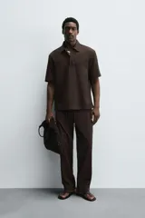 Camisa tipo polo de corte relajado confeccionada en una mezcla de lyocell y algodón. Presenta cuello con solapa, cierre frontal de botones ocultos, manga corta y un bolsillo de parche en el pecho. El bajo cuenta con aberturas laterales.