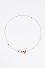 Collar tipo gargantilla compuesto por perlas blancas alargadas, con detalles de cuentas doradas. El cierre es un mosquetón dorado y el dije principal es una cabeza de pantera dorada con detalles de pedrería.