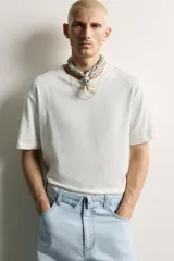 Camiseta de corte relaxed fit, confeccionada en mezcla de algodón y lino, con cuello redondo y mangas cortas.
