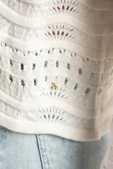 Sweater de punto calado con diseño de ondas horizontales, cuello redondo y mangas largas. Presenta un corte oversize y acabado en color blanco.