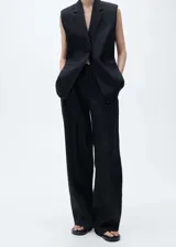 Pantalón de lino color negro, con diseño recto de tiro medio y cierre delantero con botón, gancho y cremallera ocultos. Cuenta con dos bolsillos laterales.