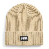 Gorro tipo beanie de punto acanalado en color beige, con vuelta en el borde y parche rectangular negro con el logo de Puma en blanco.