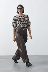 Pantalón de cuero sintético con fit barrel, de silueta amplia con volumen en las piernas y botamanga levemente entallada. Presenta bolsillos laterales y cierre frontal.