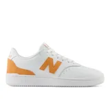 Championes New Balance modelo 80, de diseño inspirado en el básquetbol clásico. Presenta una base de cuero sintético blanco con detalles en gamuza color naranja en el logo lateral y el talón.