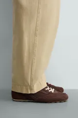 Zapatilla de estilo retro con cordones, confeccionada en una combinación de piezas de tela y cuero con acabado de gamuza. Cuenta con suela dentada en contraste.