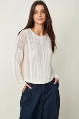 Buzo de punto color crudo, de manga larga, con diseño calado y cuello redondo.