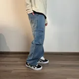 Pantalón tipo jean cargo de corte recto y tiro medio, en color azul claro lavado. Presenta bolsillos laterales con solapa y cierre de botón y cremallera.