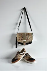 Championes de diseño urbano con combinación de tonos marrones, negros y detalles metalizados, puntera de cuero y suela blanca.