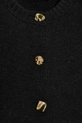 Chaqueta de punto color negro con cuello redondo, manga por debajo del codo con hombros marcados y acabados en rib. Cierre frontal con botones dorados.