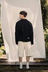 Buzo tipo polo de manga larga, color negro, con cuello y cierre parcial frontal. Presenta un pequeño bordado en el frente y la espalda.