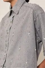 Camisa corta estilo denim color gris, de corte cuadrado, con mangas cortas y apliques brillantes en el frente y la espalda.