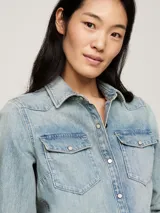 Camisa de denim celeste de manga larga con dos bolsillos en el pecho con cierre de botón.