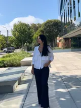 Camisa azul marino de manga larga con cuello camisero y cierre de botones. Presenta volantes horizontales en la parte delantera.