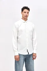 Camisa de corte regular fit confeccionada en algodón, con cuello clásico, cierre frontal de botones y bolsillo en el pecho con detalle bordado.