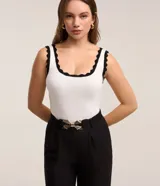 Blusa musculosa de viscosa color blanco, con escote redondo y detalles de ondas en contraste negro en el cuello y los breteles.