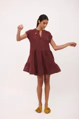 Vestido corto de lino color vino tinto, con escote en V y mangas cortas tipo musculosa. Presenta un corte holgado con volados en el ruedo.