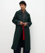 Abrigo largo de paño color verde oscuro, con solapas amplias tipo blazer, cierre frontal cruzado con botones y abertura trasera. Diseño estructurado y elegante.