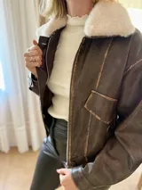 Campera de eco cuero en tono marrón con efecto desgastado, corte oversize y cierre frontal. Presenta costuras marcadas, bolsillos frontales y puños con botones.