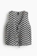 Chaleco corto de punto jacquard con estampado de zigzag en blanco y negro. Presenta escote en V y tiras finas dobles en la parte delantera para anudar.