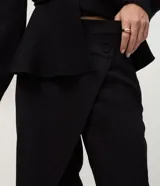 Pantalón de sastrería marca Cortelle, de corte recto y calce alineado al cuerpo. Presenta un diseño con cierre tipo cartera y superposición frontal que genera un efecto asimétrico, con cintura estructurada y botón lateral.