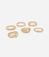 Kit de seis anillos de metal con baño en tono dorado, que presenta diversos diseños, incluyendo bandas lisas, texturizadas y modelos con incrustaciones de perlas sintéticas.