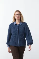 Cardigan de tejido de punto con diseño de trenzas, color azul, con cierre frontal de botones, cuello redondo y mangas largas con puños acanalados.