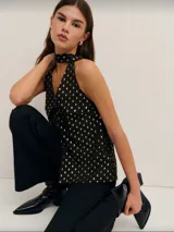 Top negro sin mangas con cuello halter y estampado de puntos dorados.