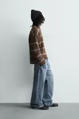 Jersey de punto con textura, corte relajado, cuello redondo y manga larga. Presenta un diseño de rayas horizontales en tonos marrones y grises con acabados en rib.
