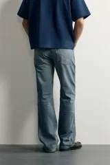 Jeans flare fit de denim rígido en color azul con efecto lavado. Presentan tiro medio, diseño de cinco bolsillos y cierre frontal con cremallera y botón.