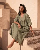 Vestido midi de lino verde militar, de corte amplio y largo, con escote en V y diseño fruncido debajo del busto. Cuenta con mangas anchas y caída fluida.